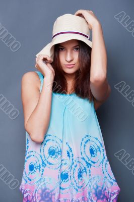 Confident woman with arms near her head holding hat against a bl
