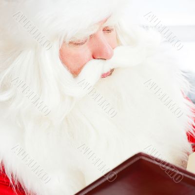 Santa sitting at home and reading a book. Indoors