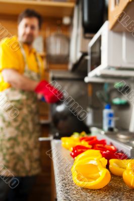 Handsome man cooking in the kitchen at home. Man on background. 