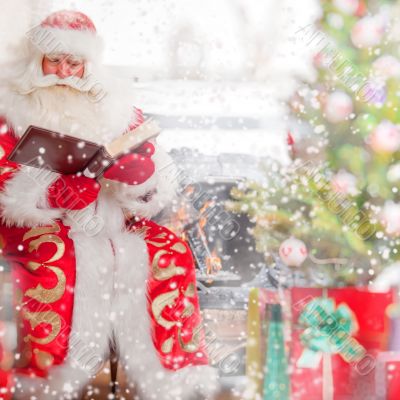 Santa sitting at the Christmas tree, near fireplace and reading 