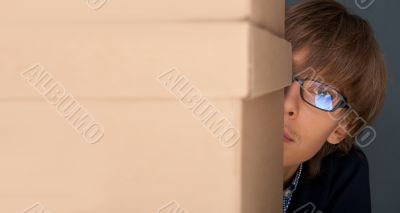 Portrait of young man holding on box against grey wall. He is st