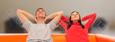 Smiling beautiful couple sitting on a sofa at their apartment an