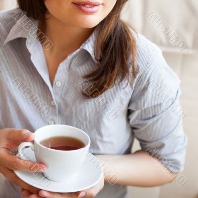 Young woman at home sipping tea from a cup