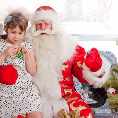 Christmas theme: Santa Claus and little girl having a fun. Indoo