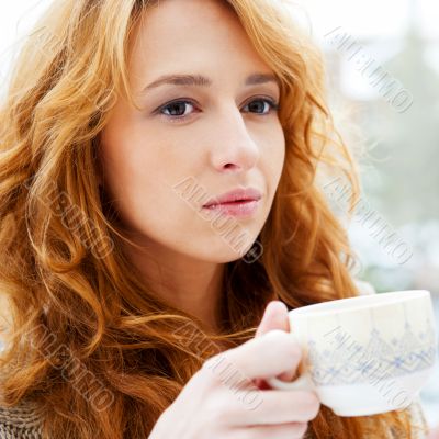 Portrait of beautiful red hair girl drinking coffee on winter ba