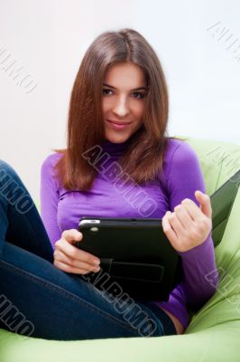 Happy young pretty woman at home, smiling and using her tablet c