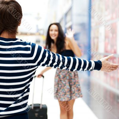 Young man meeting his girlfriend with opened arms at airport arr