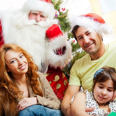 Happy family embracing and sitting on the floor in front of Chri