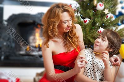 Mother and her daughter sitting together near christmas tree