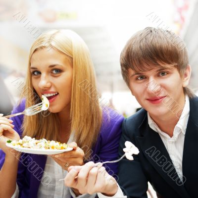 Closeup portrait of an attractive young couple eating fruit sala