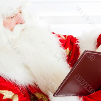 Santa sitting at home and reading a book. Indoors