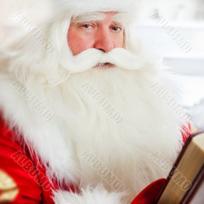 Santa sitting at home and reading a book. Indoors