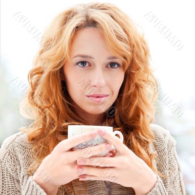 Portrait of beautiful red hair girl drinking coffee on winter ba
