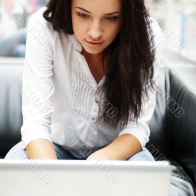 Portrait of a beautiful young woman working on laptop while sitt