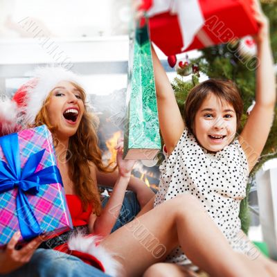 Young happy family near a Christmas tree at home holding gift an
