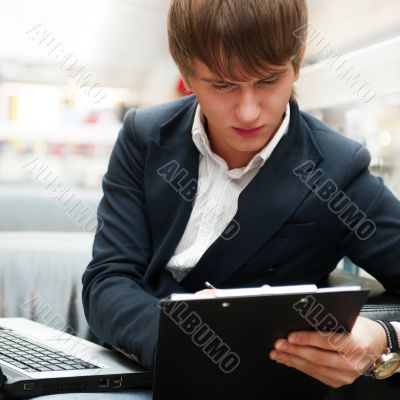 Portrait of handsome young man working with laptop at cafe at bu
