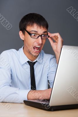 Attractive young man working with a laptop at his office. He is 