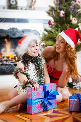 Mother and her daughter sitting together near christmas tree