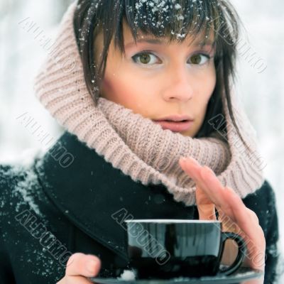 Portrait of young beautiful woman standing alone in winter park 