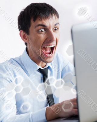 Attractive young man working with a laptop at his office. He is 