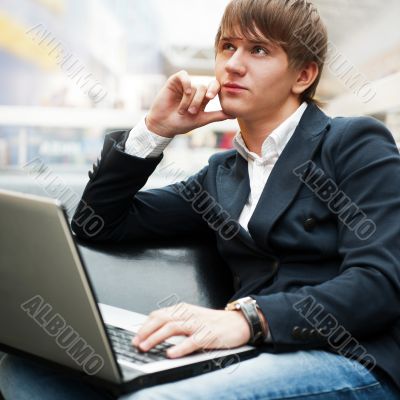 Portrait of handsome young man working with laptop at cafe at bu