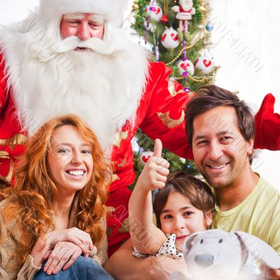 Happy family embracing and sitting on the floor in front of Chri