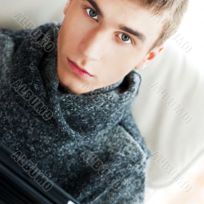 Happy young handsome man at home, smiling and using his tablet c