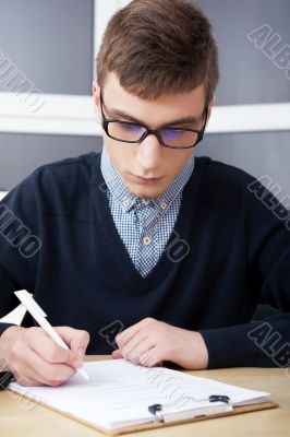 High school - Young male student write notes in classroom