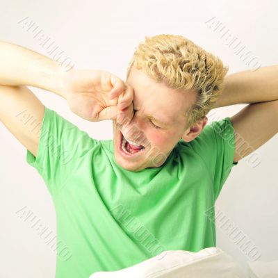 Young cheerful european man in his bed stretching for waking up.