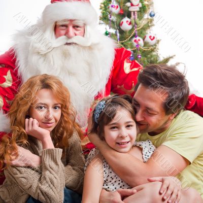 Happy family embracing and sitting on the floor in front of Chri