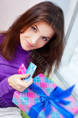 Delighted woman opening a gift sitting on the bean bag at home