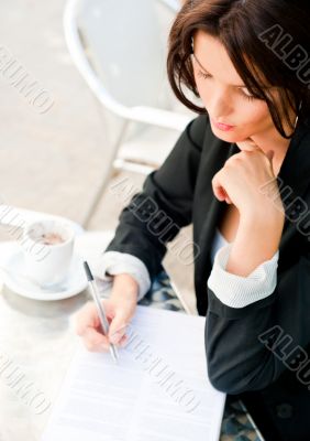Closeup portrait of pretty woman sitting at cafe and signing doc
