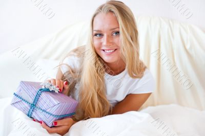Bedroom surprise present - young happy woman in bedroom