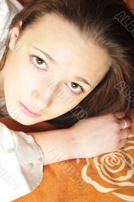 Closeup portrait of young pretty girl laying on her bed