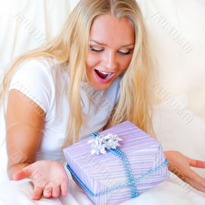 Bedroom surprise present - young happy woman in bedroom
