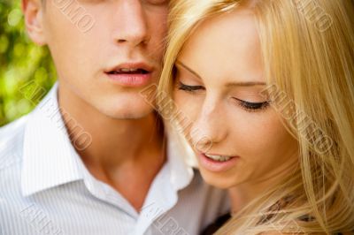Portrait of beautiful young couple standing against green tree i
