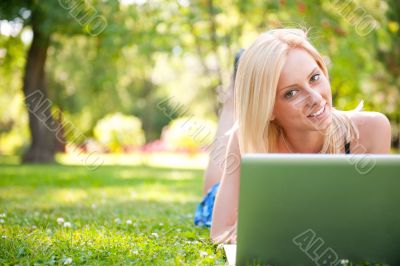 Portrait of young pretty woman resting on green grass at summe