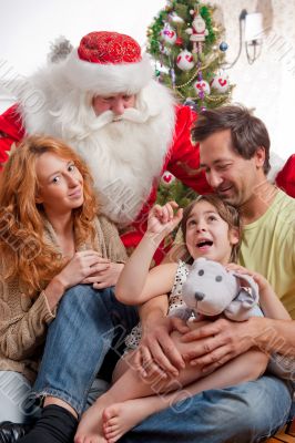 Happy family embracing and sitting on the floor in front of Chri