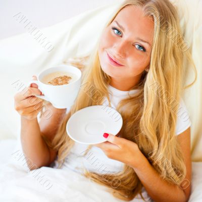 Young woman at home sipping tea or coffee from a cup