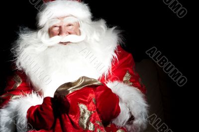 Santa sitting at the Christmas room and looking into the sack