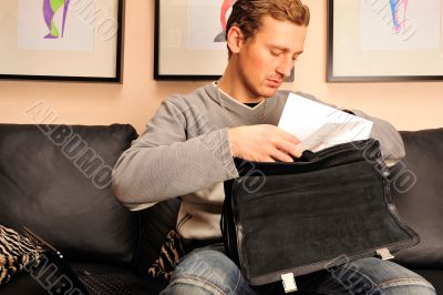 Happy young man sitting on sofa at home 