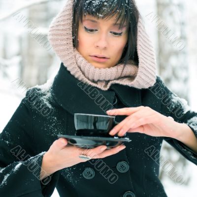 Portrait of young beautiful woman standing alone in winter park 