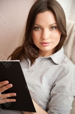 Portrait of a happy young brunette woman holding book