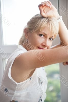 Closeup portrait of smiling woman standing near big window