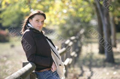 Woman leaning against fence on farmland