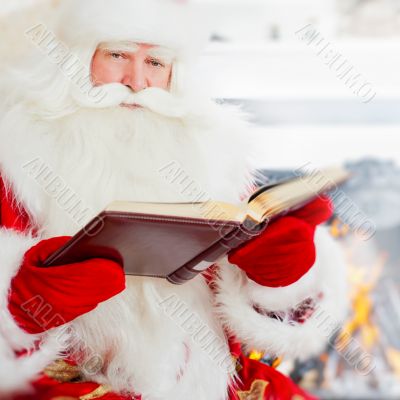 Santa sitting at home and reading a book. Indoors