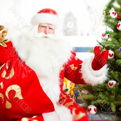 Santa sitting at the Christmas tree, near fireplace and looking 