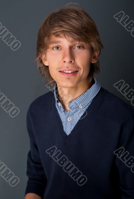 Portrait of young relaxed business man leaning on grey wall look