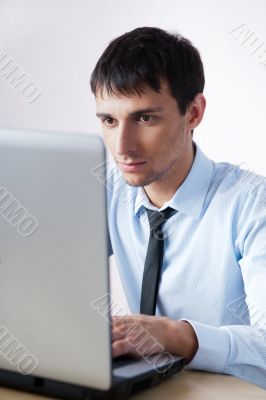 Attractive young man working with a laptop at his office
