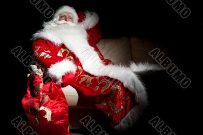 Santa sitting with a sack indoor at dark night room